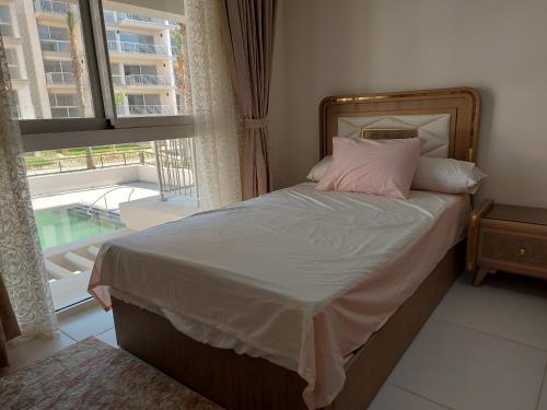 Bett mit rosa Kissen in einem Zimmer mit Fenster in der Unterkunft Marassi Marina in El-Alamein