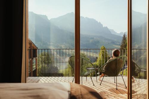 a man sitting in chairs on a balcony with a view at Hotel Lech Da Sompunt in Badia