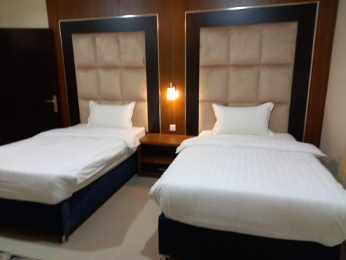 two beds in a hotel room with white sheets at الملاك بارك in Taif
