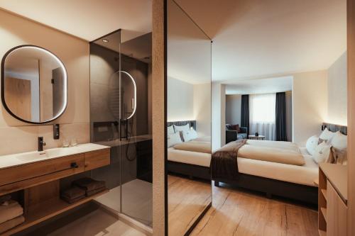 a bathroom with a bed and a sink and a mirror at Hotel Lech Da Sompunt in Badia