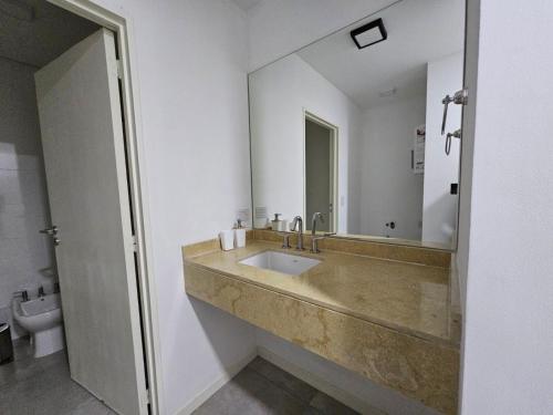 y baño con lavabo con espejo y aseo. en Departamento de categoría en Salta Capital en Salta
