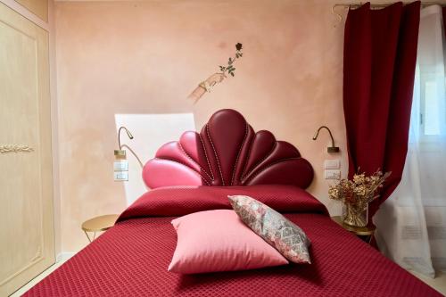 a red bed with pink pillows on top of it at Agriturismo Borgonuovo in Rimini