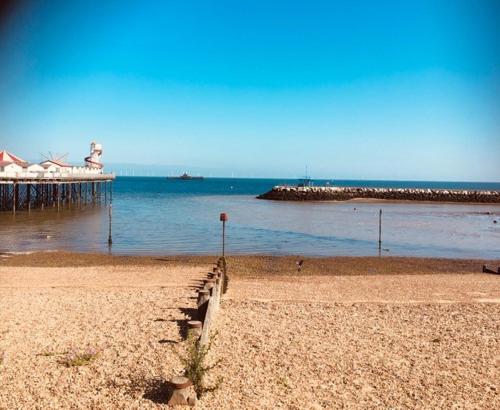 a beach with a pier and the ocean with at Seaside Villa on Secluded Green in Herne Bay