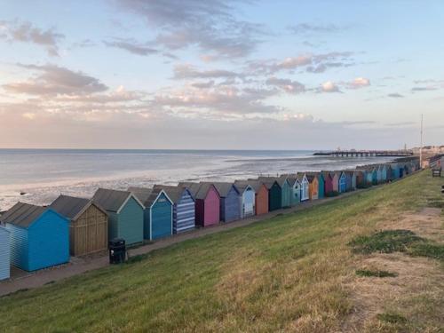 a row of colorful beach huts on the beach at Seaside Villa on Secluded Green in Kent