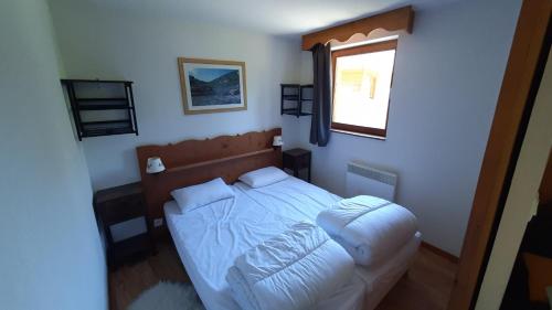 a bedroom with a white bed with a window at Charmant appartement au pied des pistes in Chamrousse
