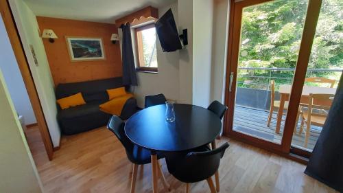 un salon avec une table, des chaises et un canapé dans l'établissement Charmant appartement au pied des pistes, à Chamrousse