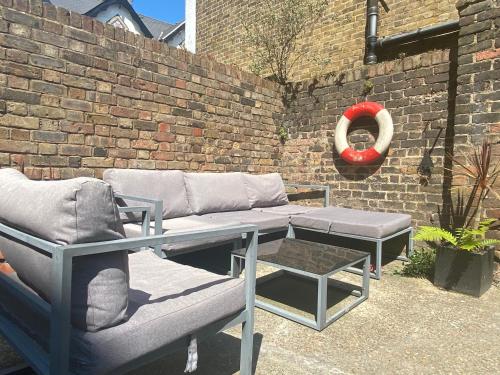 un patio con divano, tavolo e muro di mattoni di Stylish Garden Flat a Deal