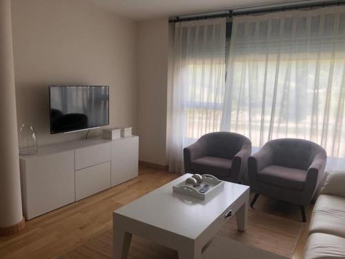 sala de estar con 2 sillas y TV en Apartamento Boutique Arquera Golf II -Llanes en Llanes