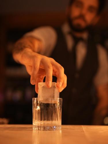 a man placing a cube of ice in a glass at Grand Mercure Curitiba Rayon in Curitiba