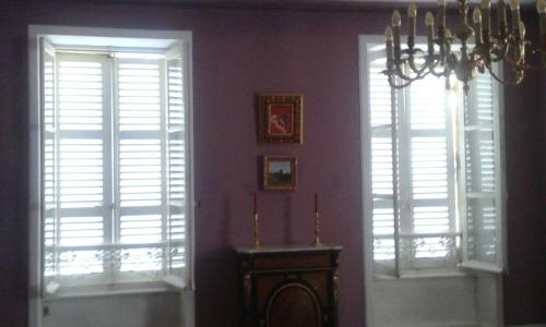 twee ramen met witte luiken in een kamer met een tafel bij Chambre d'hôte, 3 pièces 90m2 in Autun