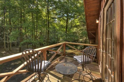 two chairs and a table on a deck with trees at Keepin it Reel in Ellijay