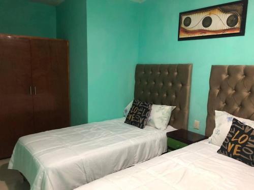 two beds in a bedroom with blue walls at El sueño de Maria in Veracruz