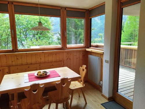 a dining room with a table and chairs and windows at Appartamento I Larici in Folgarida
