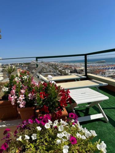 a balcony with flowers and a picnic table on top at Piccadilly Penthouse with Jacuzzi in Lido di Camaiore