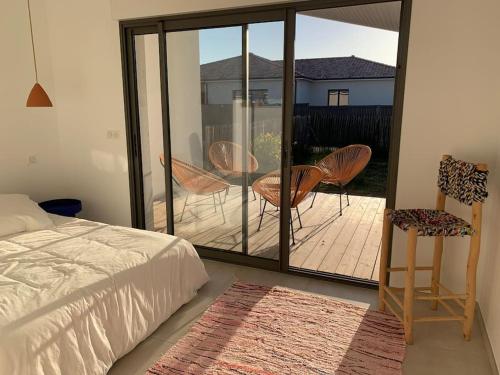 une chambre avec un lit et un balcon avec des chaises dans l'établissement Maison de plage Montalivet, à Vensac