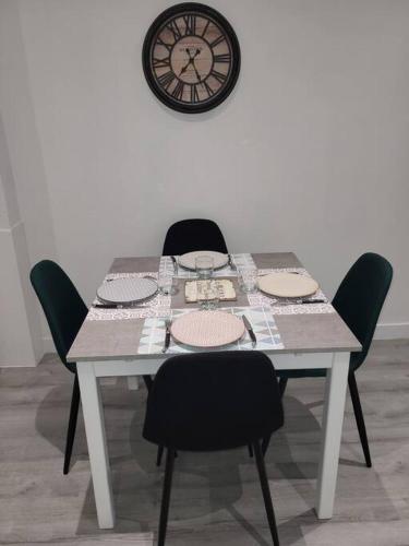 une table avec des chaises et une horloge sur le mur dans l'établissement Grand studio refait à neuf centre-ville, à La Bourboule