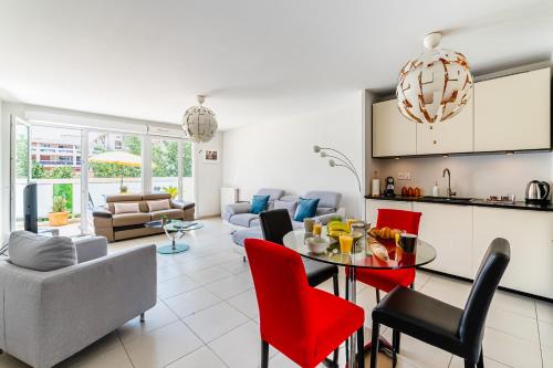 Il dispose d'une cuisine et d'un salon avec une table et des chaises rouges. dans l'établissement Élégant appartement à deux pas du Vélodrome - Emplacement idéal à Marseille, à Marseille