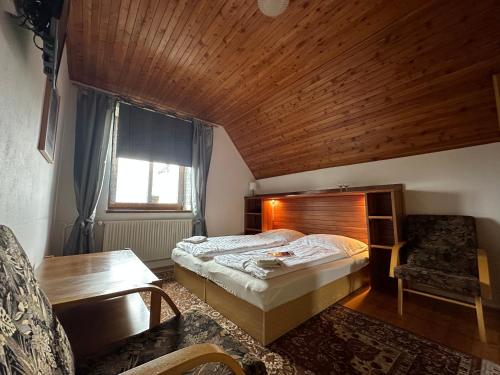 a bedroom with a bed and a wooden ceiling at Penzion Harvanek in Vlachovice