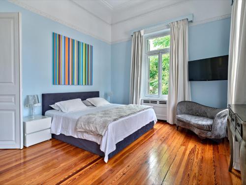 1 dormitorio con paredes azules, 1 cama y 1 silla en The White House in Plaka by JJ Hospitality en Athens