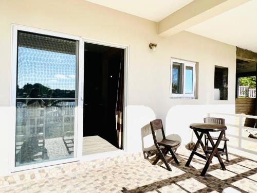 a patio with a table and chairs and a balcony at SeaLaVie Apartments - Grenada in Saint Georgeʼs