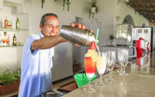 a man is making a drink in a bar at Seabel Aladin Djerba in Aghīr