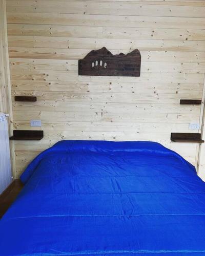 a bedroom with a blue bed with a wooden wall at Casa vacanze la torre in Malonno