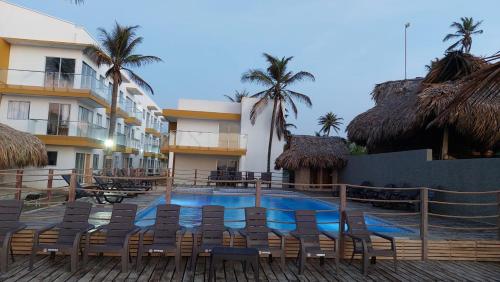 un complejo con una piscina con sillas y un edificio en NAHIR apartamento de playa en condominio Palmar del viento, en San Bernardo del Viento