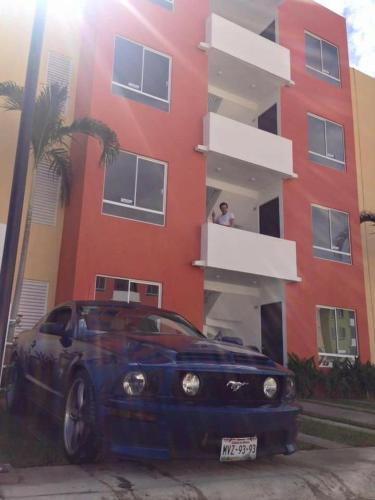 une voiture bleue garée devant un bâtiment rouge dans l'établissement Depto real del palmar, à Aguacatillo