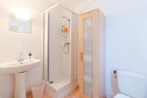 a white bathroom with a shower and a sink at Charmante maison à nbne plage in Narbonne