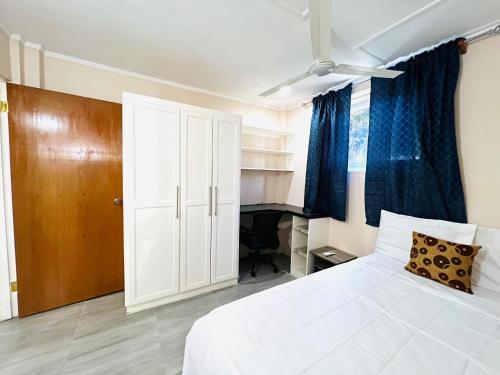 a bedroom with a white bed and blue curtains at SeaLaVie Apartments - Grenada in Saint Georgeʼs
