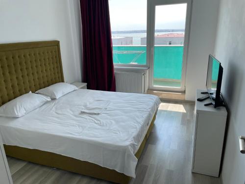 a bedroom with a bed with a television and a window at Apartament Summerland Crazy Beach Mamaia in Mamaia