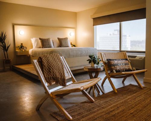 um quarto com uma cama, 2 cadeiras e uma mesa em Brut Hotel em Tulsa