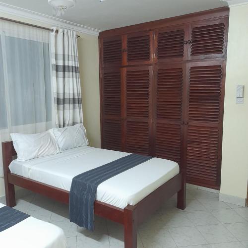 a bedroom with a bed and a wooden cabinet at Chloe Isla Apartment Malindi. in Malindi