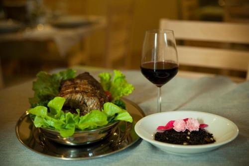 einen Teller Fleisch und ein Glas Wein und Salat in der Unterkunft Appartamento del Monastero in Dronero