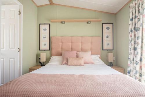 a bedroom with a large bed with a pink headboard at The Woodlark Lodge at Rockley Park in Lytchett Minster