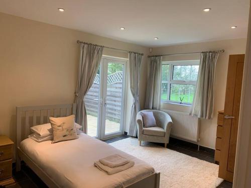 a bedroom with a bed and a chair and a window at The Old Dairy in Mersham