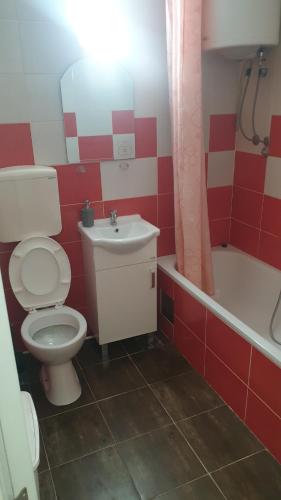 a red and white bathroom with a toilet and a sink at Apartmani Borko 1-1 in Loznica