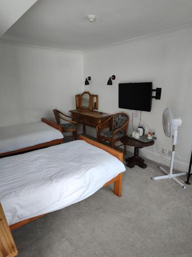 a bedroom with two beds and a desk and a television at The Northwick Arms Hotel in Evesham