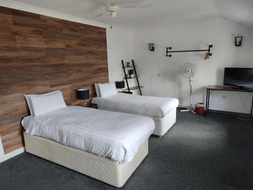 a room with two beds and a desk and a television at The Northwick Arms Hotel in Evesham