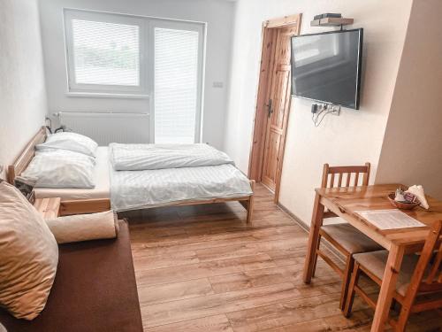 a room with two beds and a table and a television at Rezidencia Podhájska in Podhájska