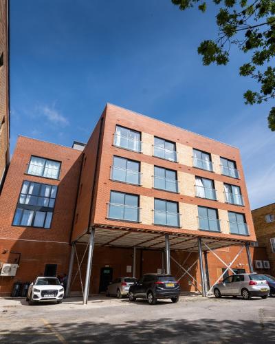 a brick building with cars parked in a parking lot at Hemel Apartments- Elite Escape in Hemel Hempstead