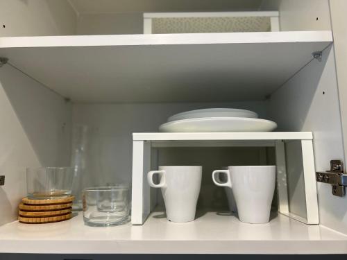 a white cabinet with two cups and plates on it at Athesa Apartments Downtown Dubai Business Bay in Dubai