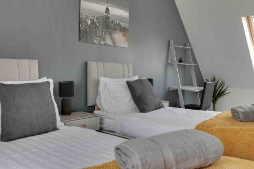 a bedroom with two beds and a chair at Elizabeth II Five Bedroom Spacious Home in Bocking Churchstreet