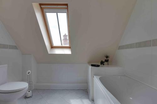 a white bathroom with a toilet and a bath tub at Elizabeth II Five Bedroom Spacious Home 