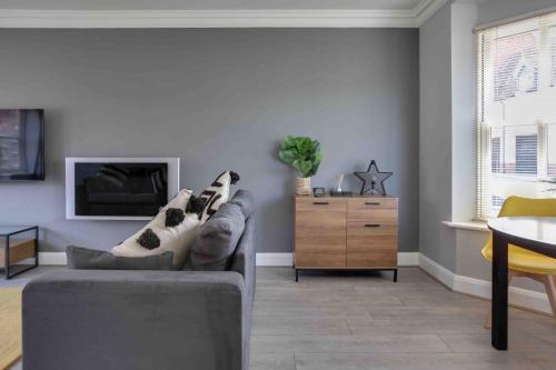 a living room with a gray couch and a table at Elizabeth II Five Bedroom Spacious Home in Bocking Churchstreet