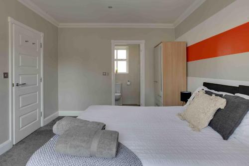 a bedroom with a large bed with an orange accent at Elizabeth II Five Bedroom Spacious Home in Bocking Churchstreet