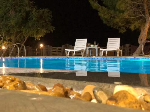 a swimming pool at night with two chairs and a table at Talet kokash in Al Salt