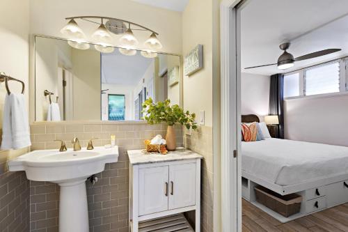 een badkamer met een wastafel en een spiegel en een bed bij Hale Ono Loa 117 in Kahana