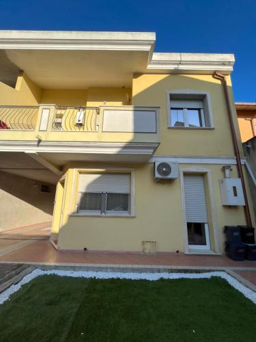 a yellow house with a lawn in front of it at Welcome Home Quartu Sant'Elena in Quartu SantʼElena