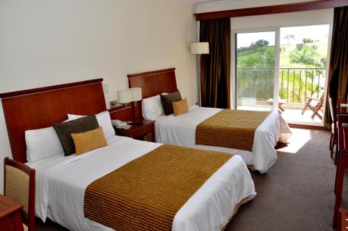 a hotel room with two beds and a balcony at Sol Victoria Hotel SPA & Casino in Victoria